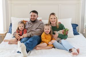 Family lounging together on white bedding while enjoying quality time at home.