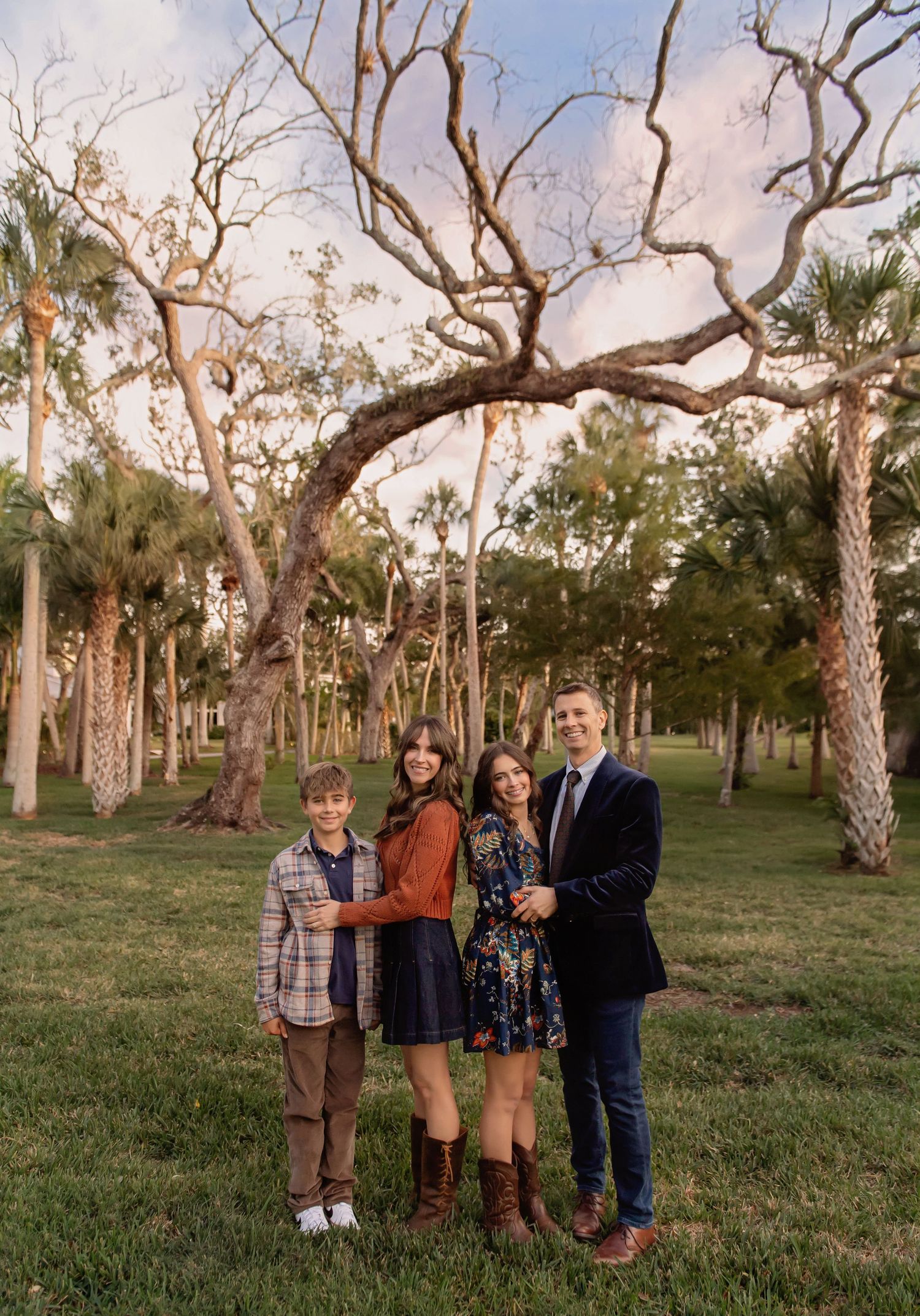 Group portrait taken in a wooded area with palm trees and twisted branches overhead.