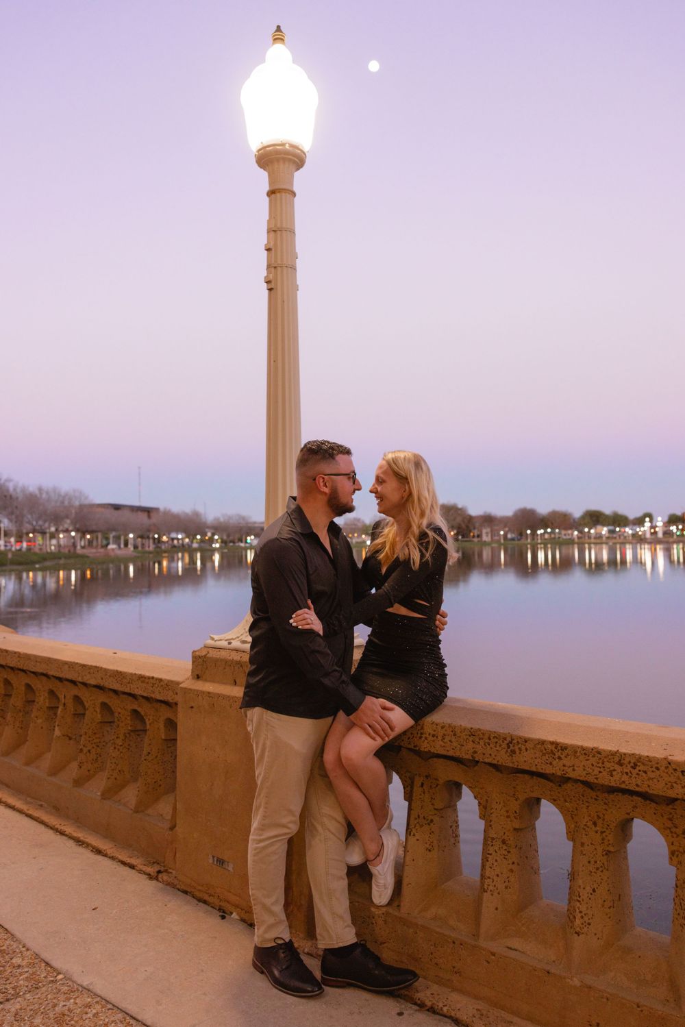 Couple posing by waterfront at sunset in downtown Lakeland Florida during engagement session