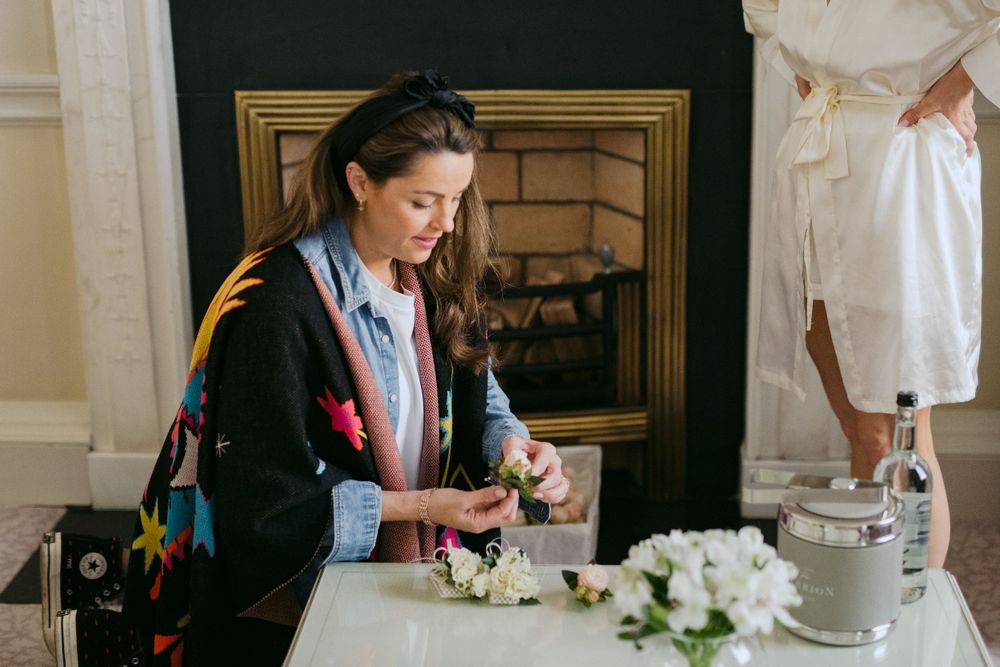 Event planner arranges white flowers at an elegant indoor venue with a fireplace in the background.