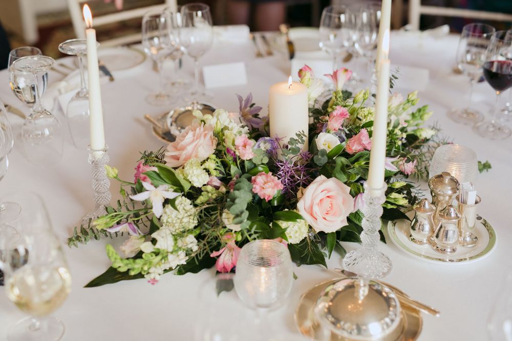 White and pink floral centerpiece with tall candles on an elegant wedding reception table.