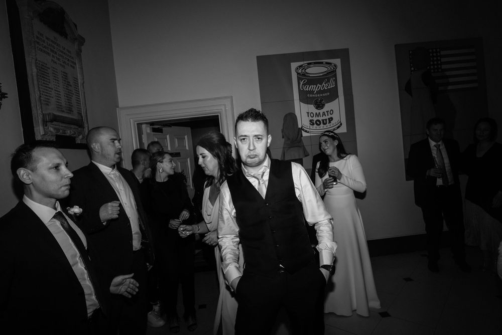 A black and white photo of people dancing and socializing at a formal event with people dressed in evening attire.
