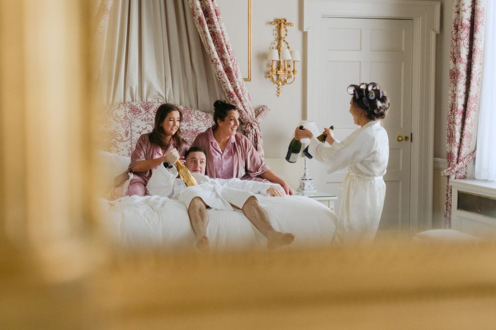 A cozy family gathering on a white bed in an elegant hotel room with vintage decor and curtains.