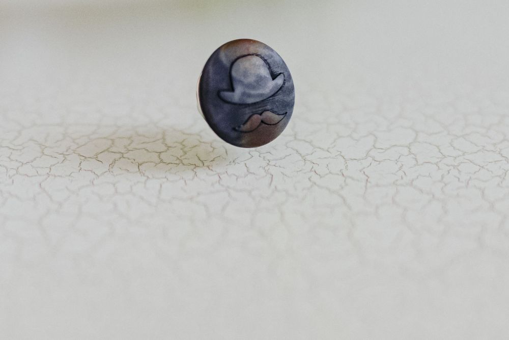 A dark blue glass marble rests on a textured off-white surface creating a minimalist composition.