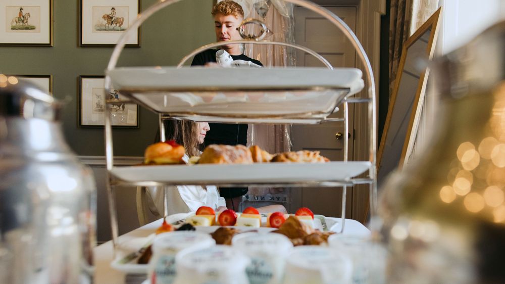 Elegant tiered serving stand displays desserts and treats on white plates in an upscale dining setting.