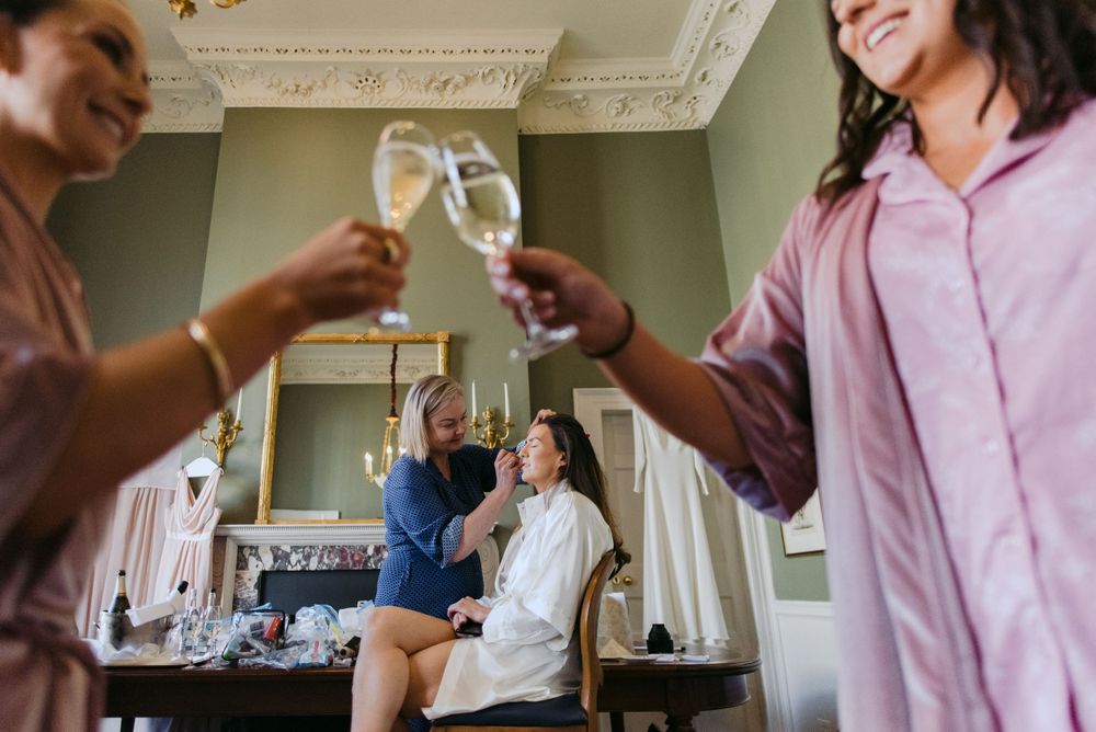 People raise champagne glasses in celebration inside an elegant room with ornate crown molding details.