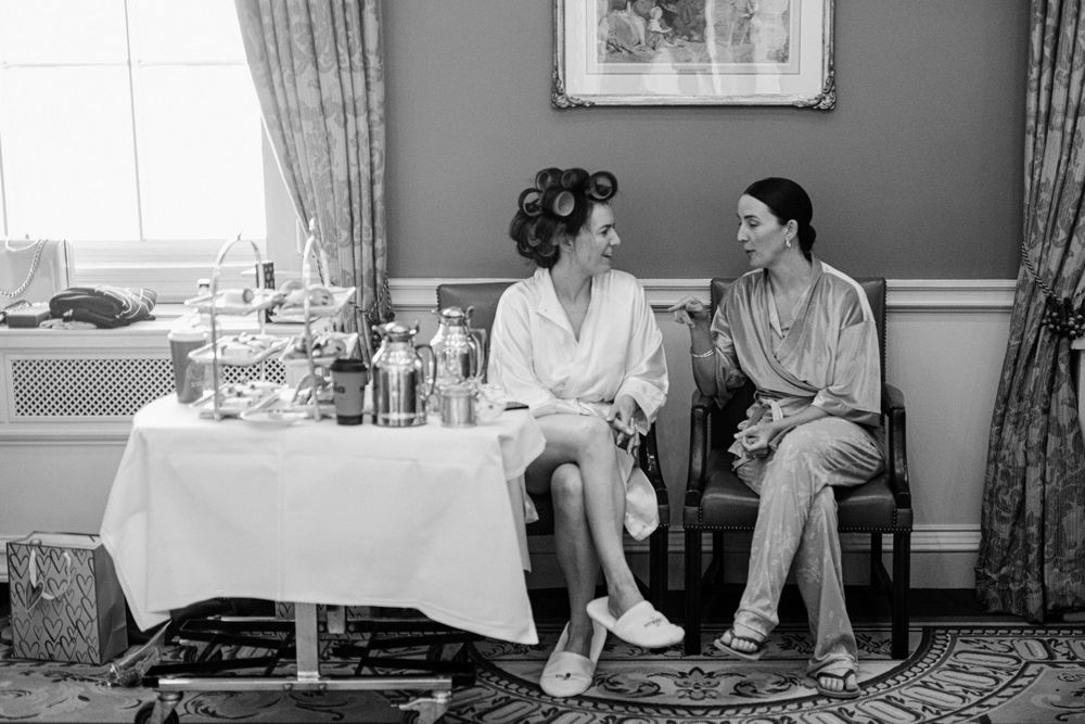 Two people sitting and chatting in white robes near a table set for service in an elegant room.
