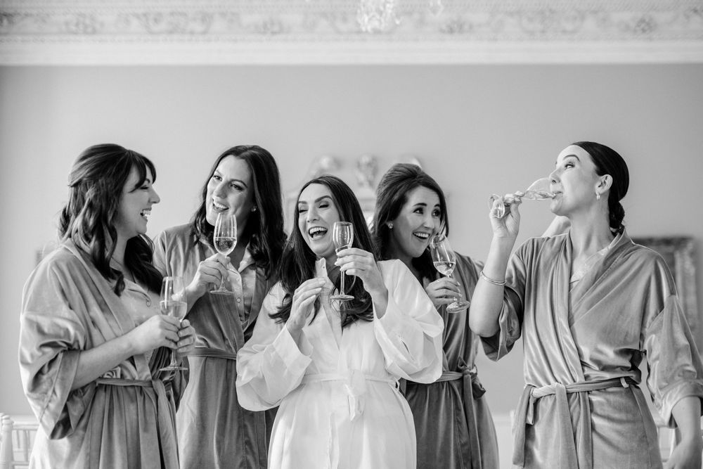 Black and white photo of group celebrating together in matching robes while drinking and laughing.