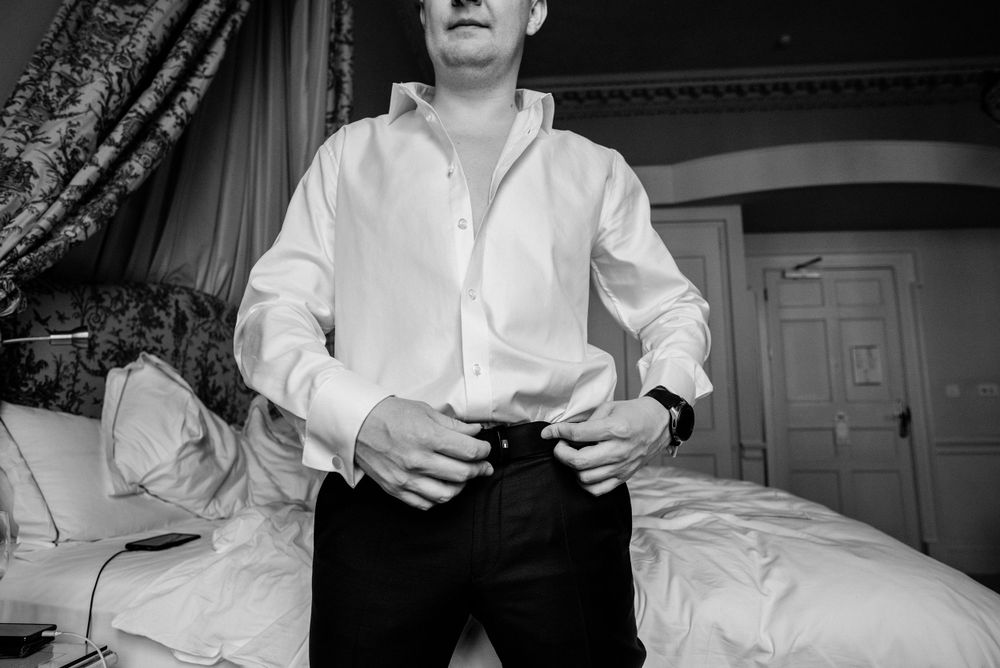 Black and white vintage photo showing someone in a white button-down shirt and dark pants standing in a bedroom.