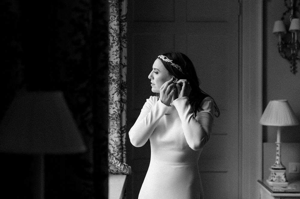 A person in a white dress listens through headphones in a dramatic black and white composition.