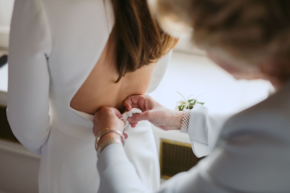 A close-up view of a bracelet or watch being fastened onto a wrist in a white formal setting.