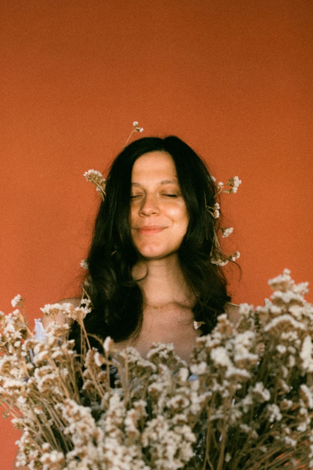 A series of dreamy portraits with white flowers against a warm terracotta background.