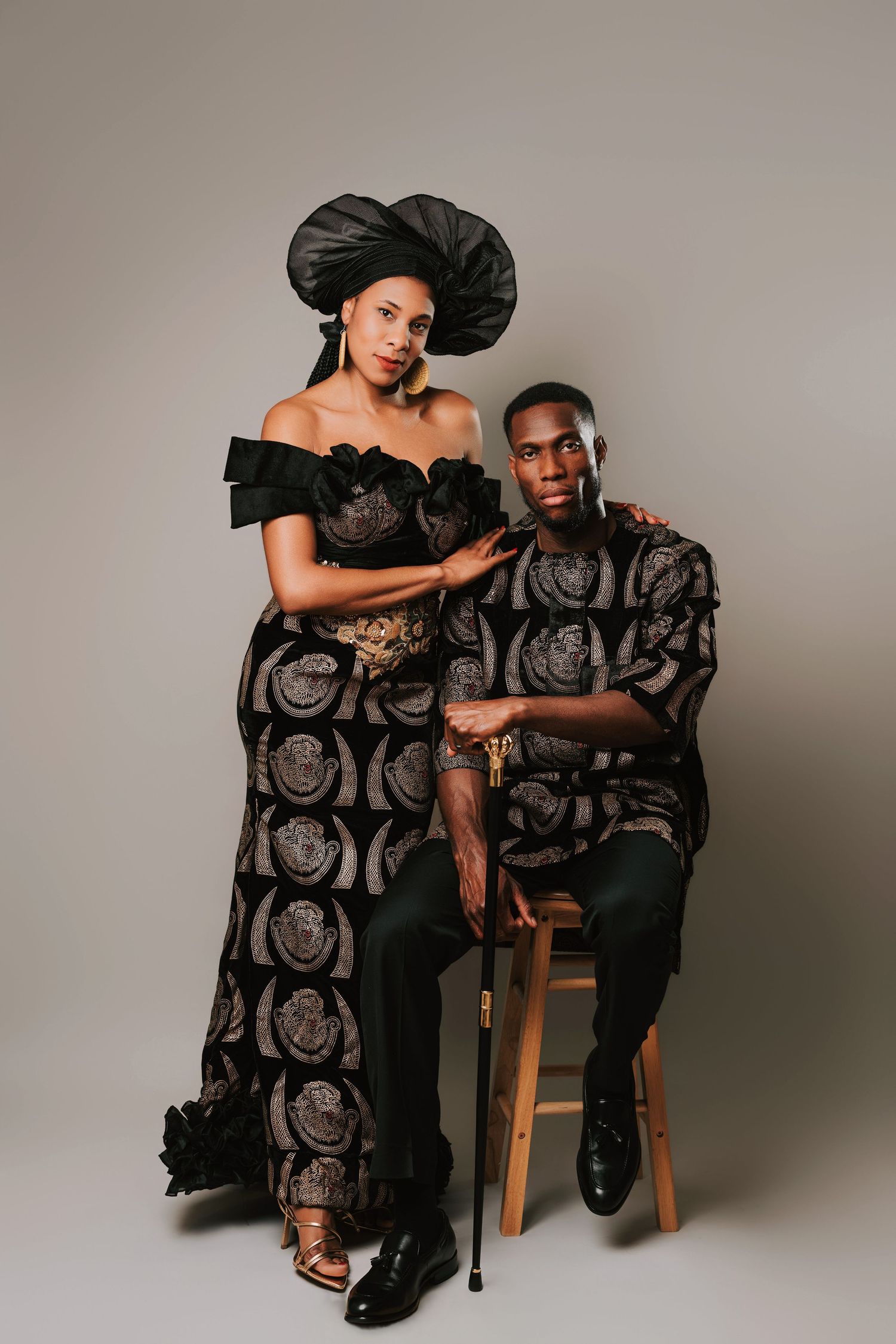 Couple in matching black and gold African traditional attire posing elegantly in a studio setting at Fatima Photography in Basildon.