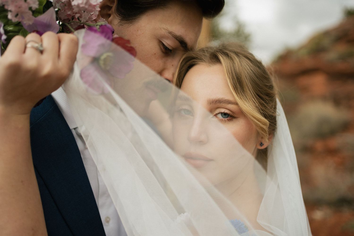 An artistic wedding photo showing a couple through delicate veil fabric.