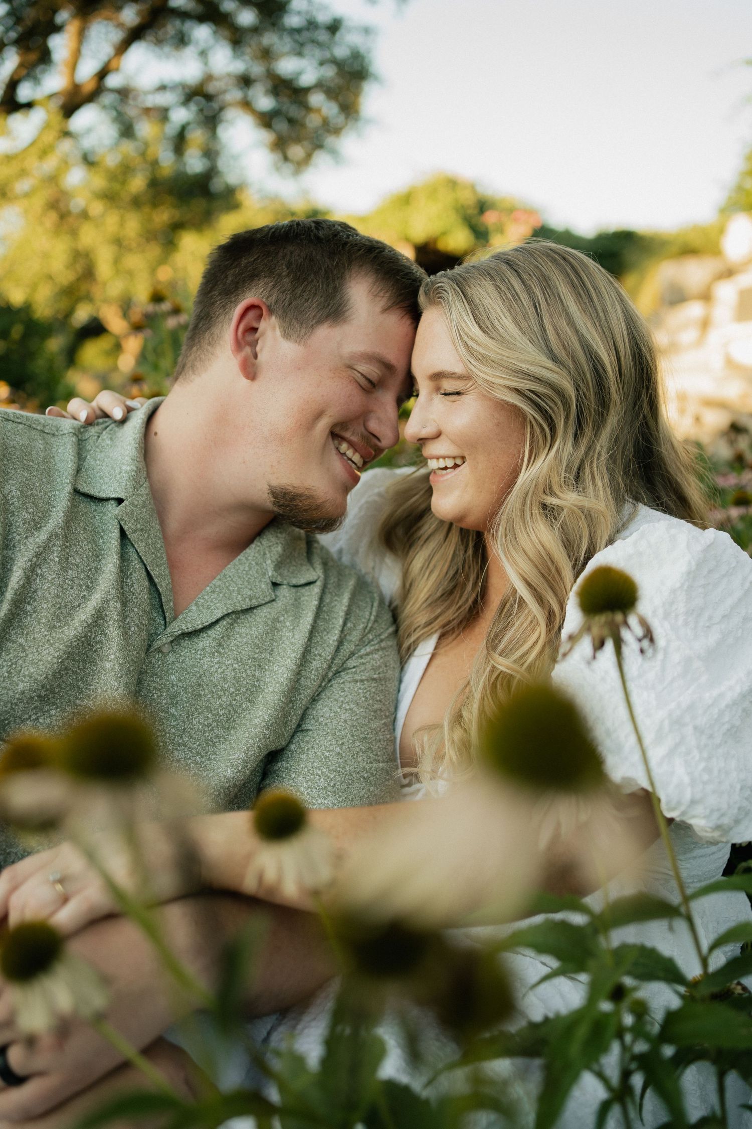 A couple shares a joyful intimate moment together in a sunlit garden.