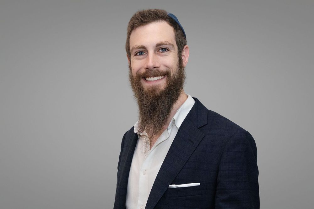 Professional headshot series showing person in navy suit with full beard against gray background.