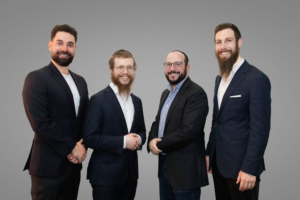 A group of professionals in dark suits pose together for a series of corporate headshots against a gray background.