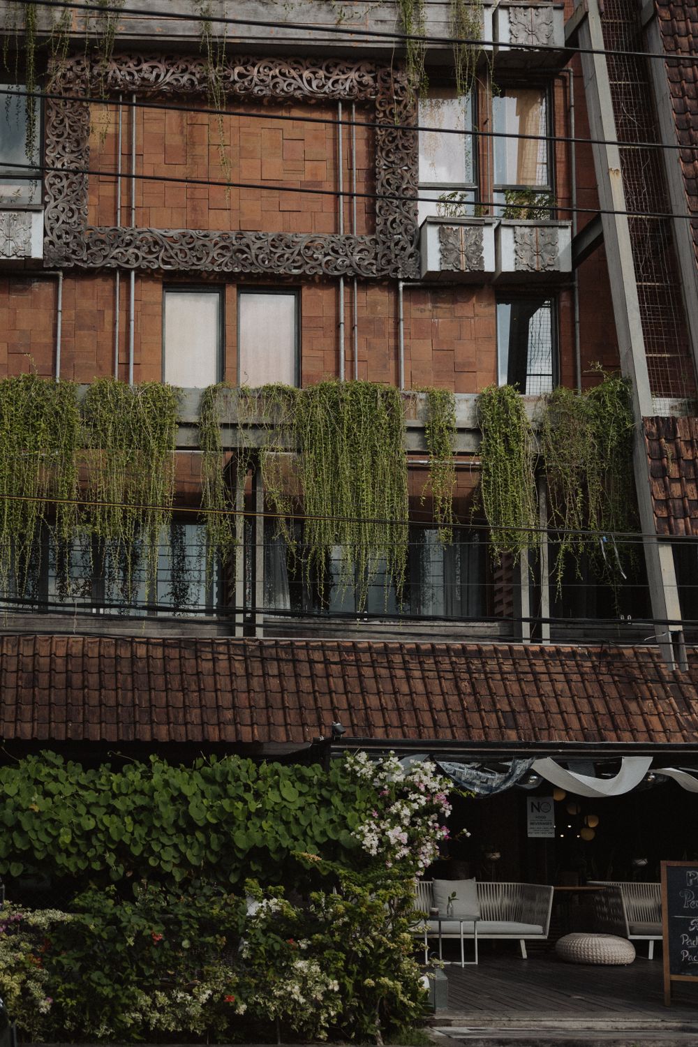Modern brick building exterior with hanging plants and glass balconies.