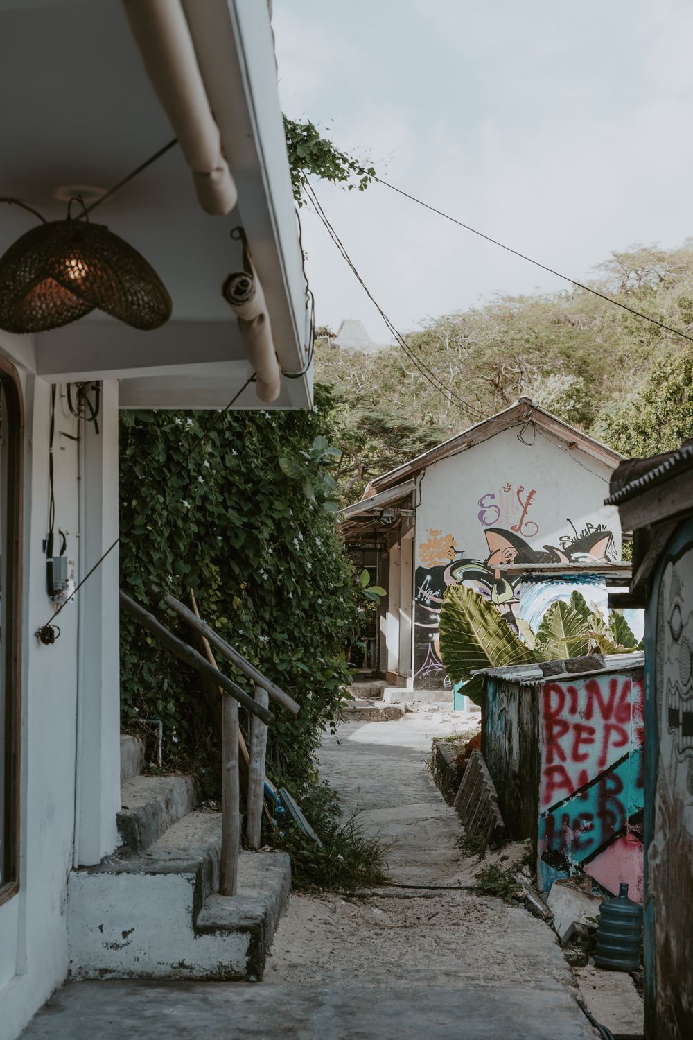 White-walled pathway with graffiti art leading through a hillside village.