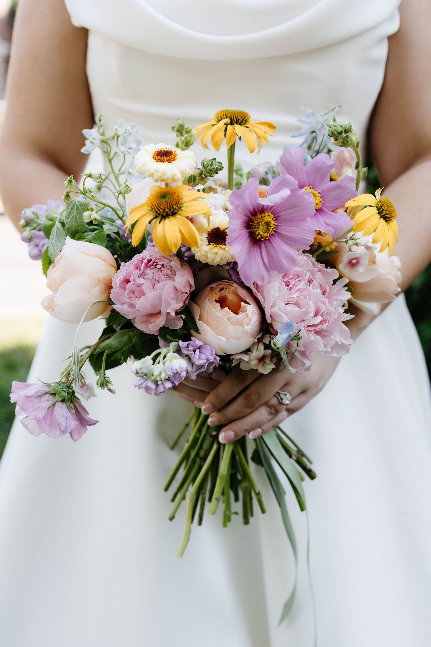 Bride’s hands holding a colorful mixed flower wedding bouquet