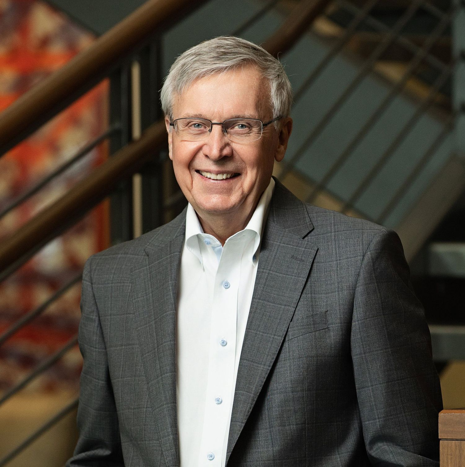 Business headshots of person in gray suit and white shirt against industrial background.