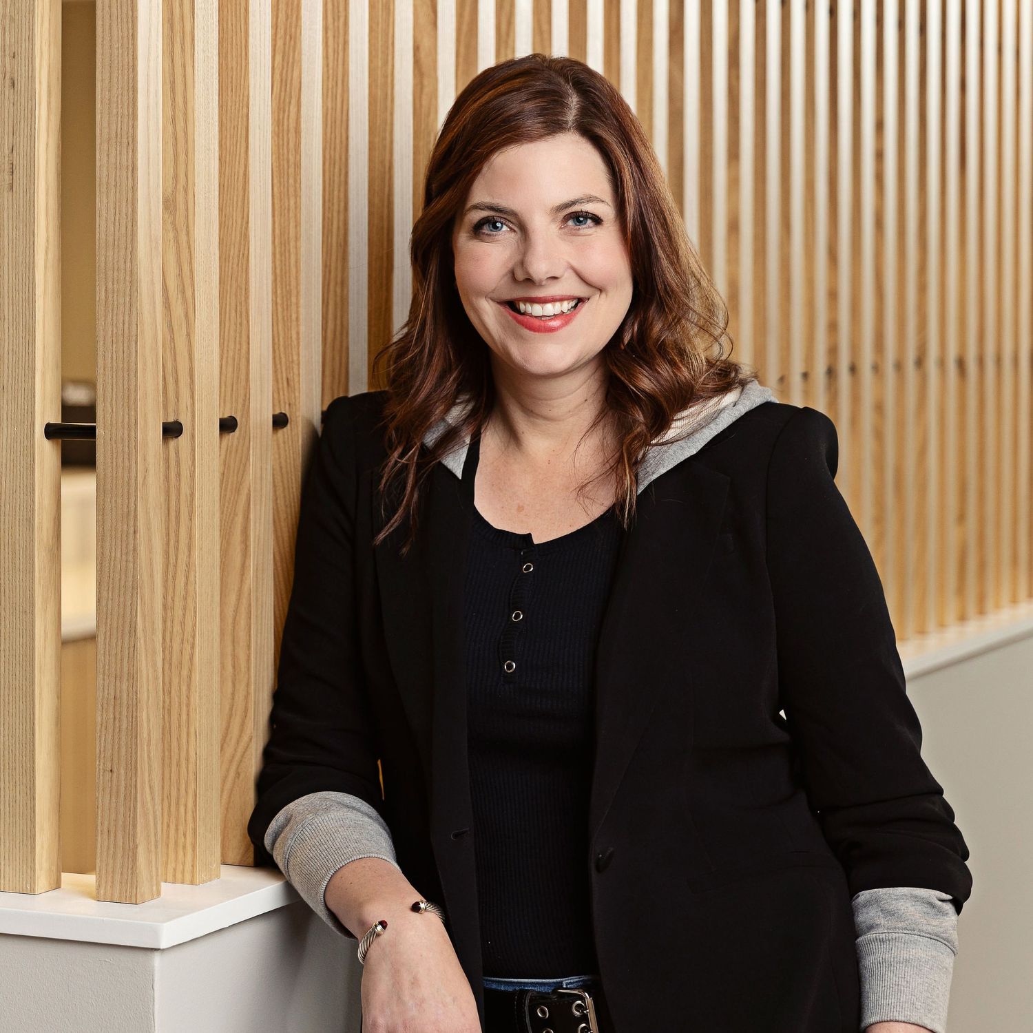 Professional headshots of individuals in black attire against a wooden slat background.