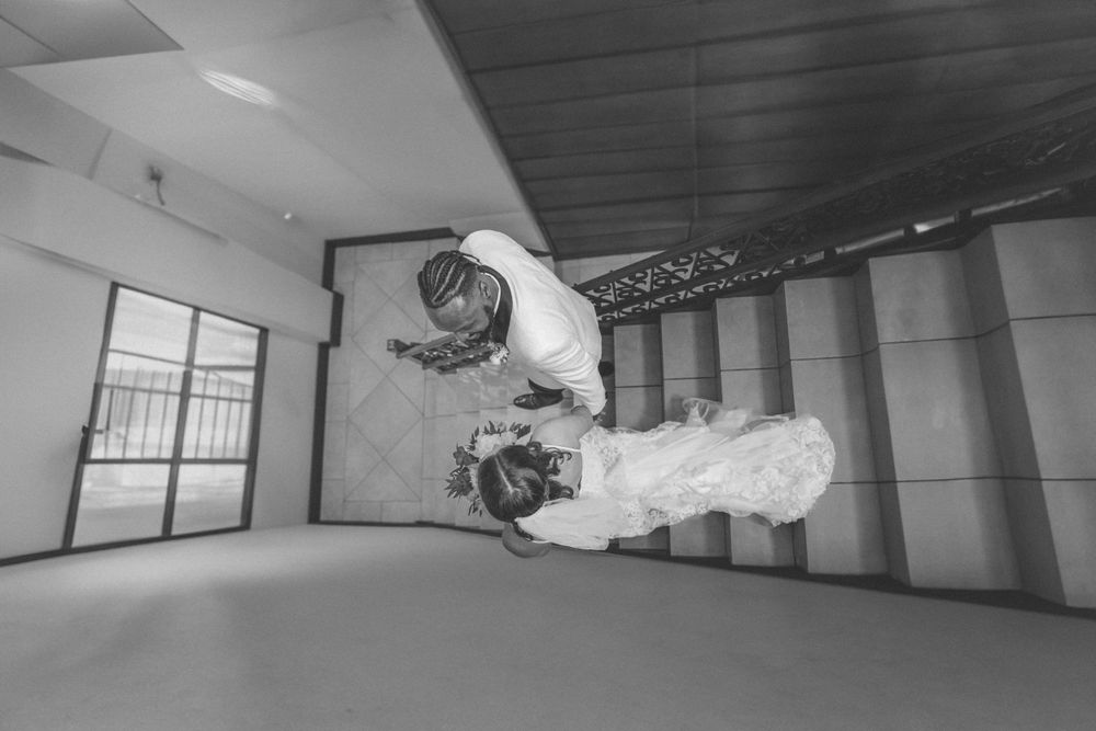 Dynamic black and white photograph capturing acrobatic dance move on an empty studio floor.