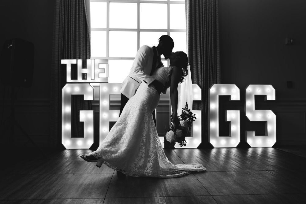 Silhouetted couple embracing in front of illuminated marquee letters spelling GREGGS.