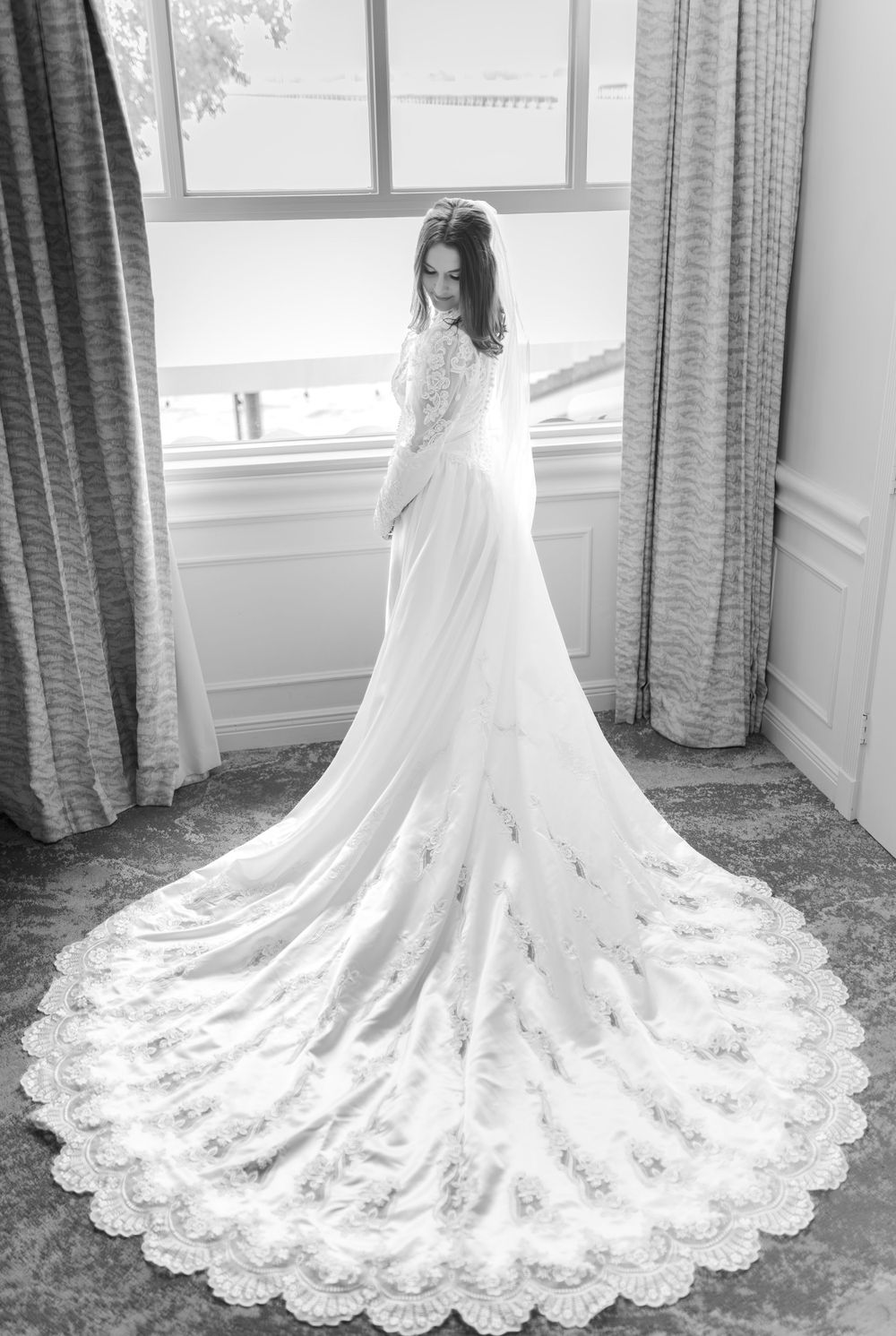 Stunning lace wedding dress with long train photographed from behind in black and white.