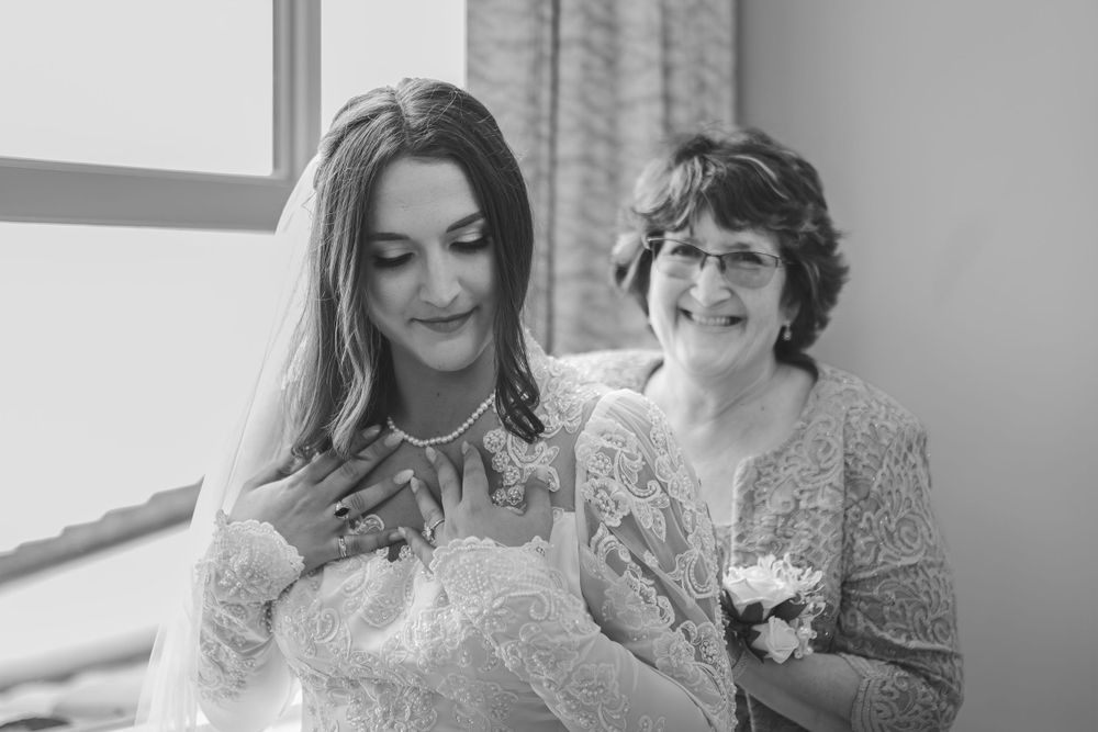 Intimate wedding moment captured in black and white by a window.