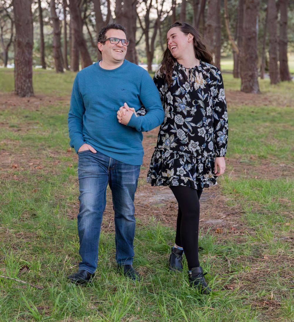 A couple walking together through a pine forest on a casual afternoon.