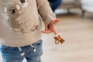 Small gingerbread cookie held in hand while wearing beige koala sweatshirt and jeans.