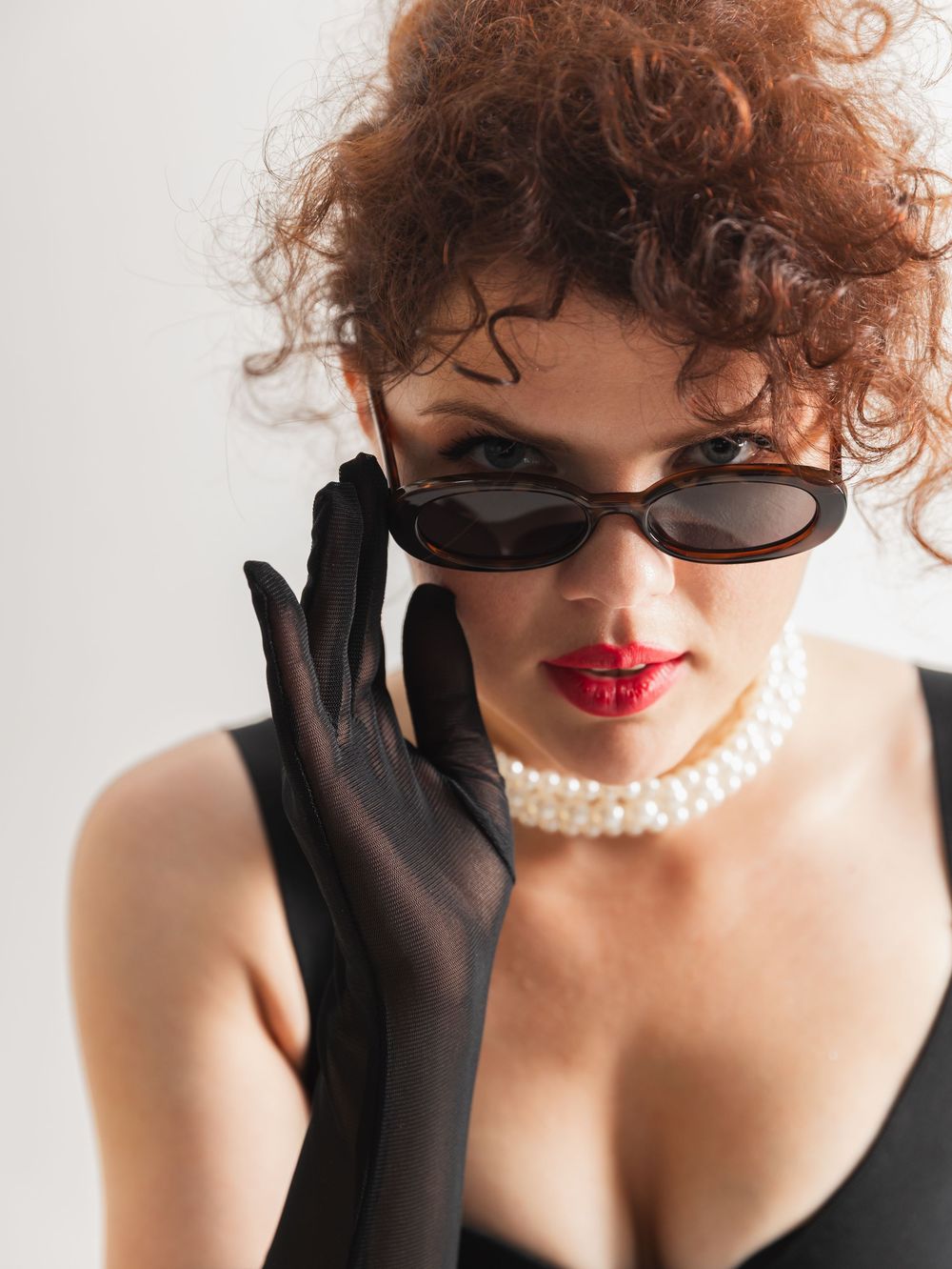 Glamorous retro-styled portrait featuring red lips, pearl necklace, and black gloves.