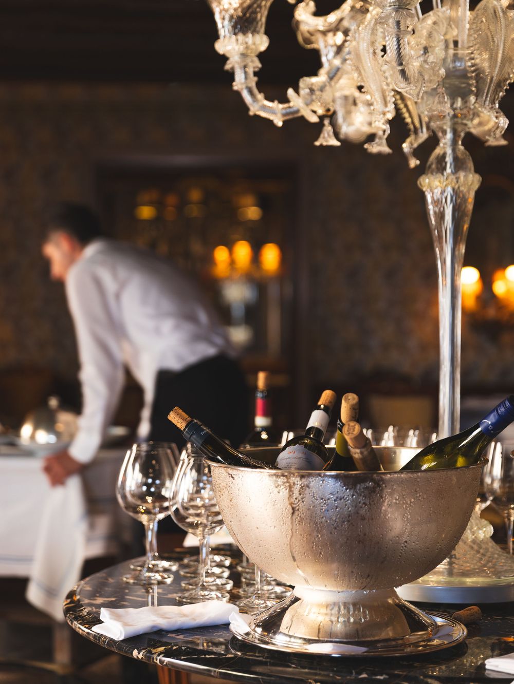 Elegant table setting with champagne bottles in ice buckets and crystal stemware.