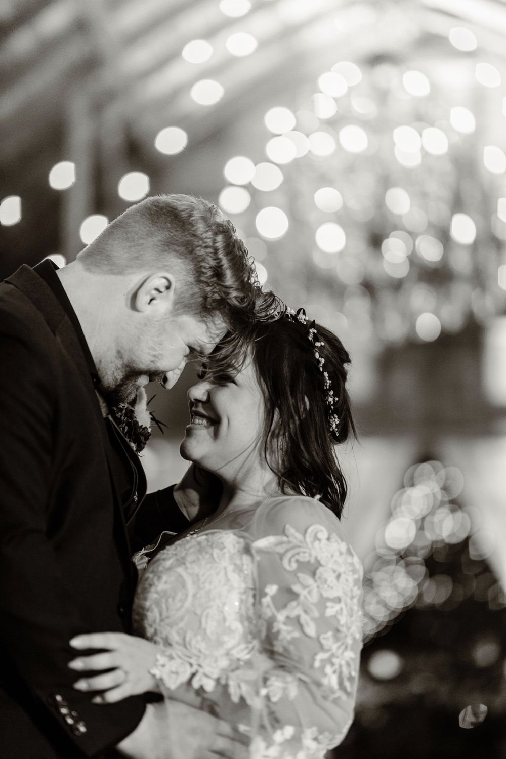 Black and white portrait of couple sharing intimate moment with sparkling bokeh background.