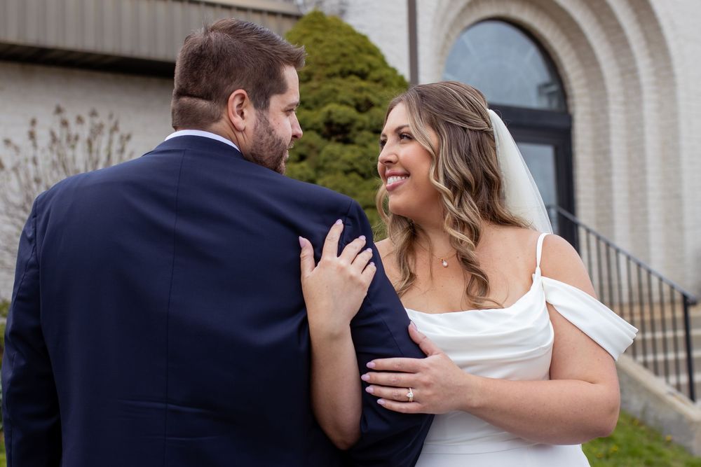 A joyful couple shares a happy moment together outside a building with arched architecture on their wedding day.