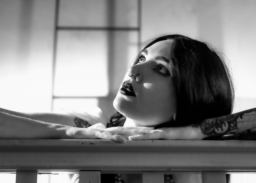 Dramatic black and white portrait in soft lighting with artistic shadows.