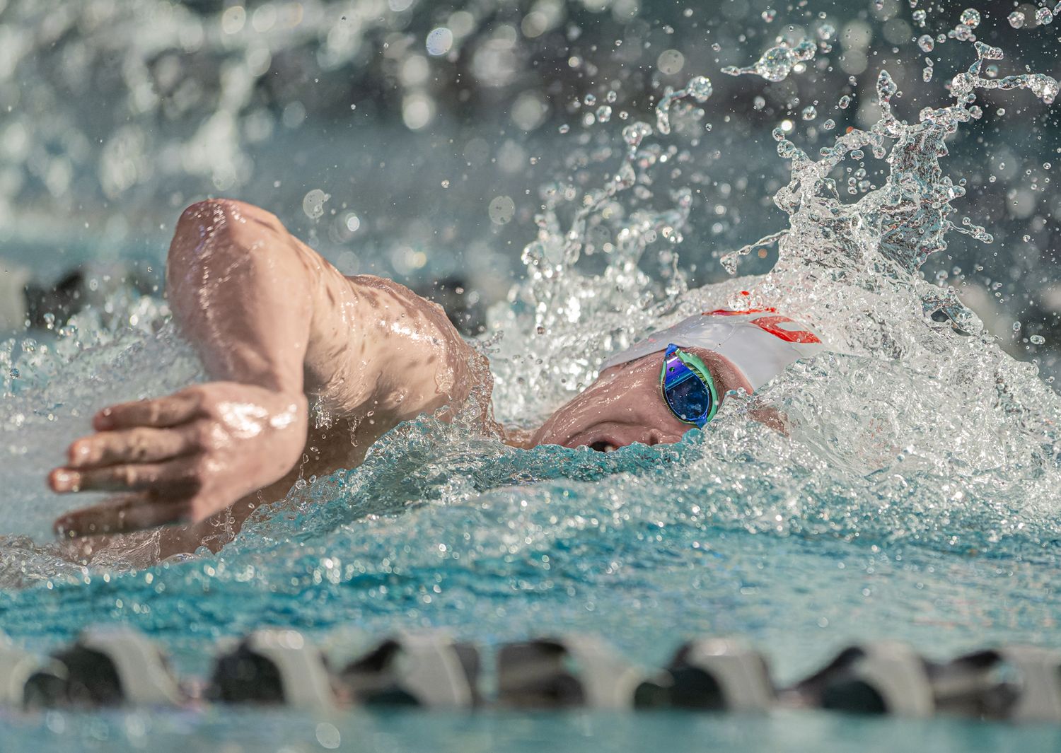 Close-up of freestyle swimmer in action with water splashing during competitive race.