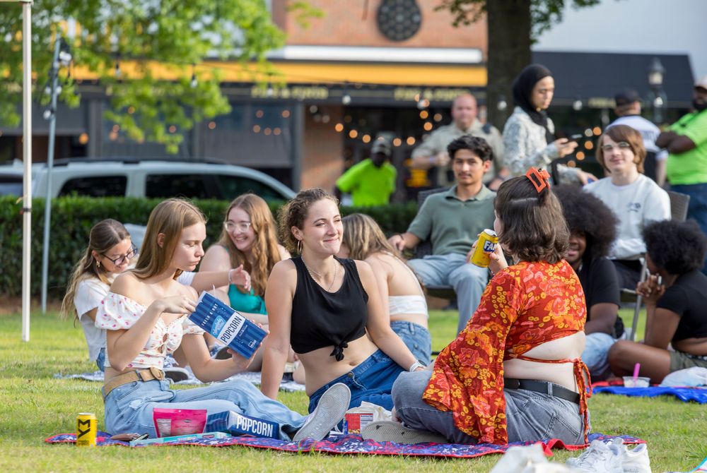 Group of people enjoying outdoor picnic on grass at community gathering.