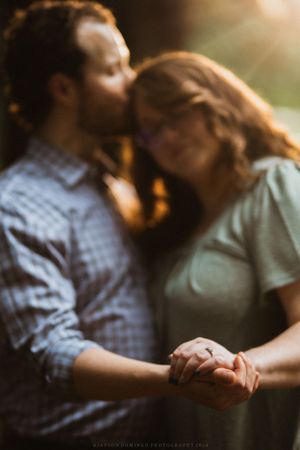 Intimate couple holding hands in warm sunset lighting.
