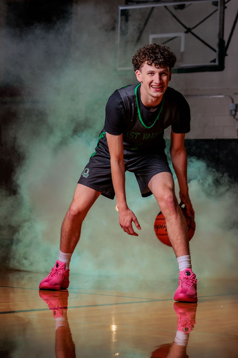 East Valley High School basketball player portrait by Chris Elam Photography in Spokane, WA, featuring a athlete with green smoke dribbling