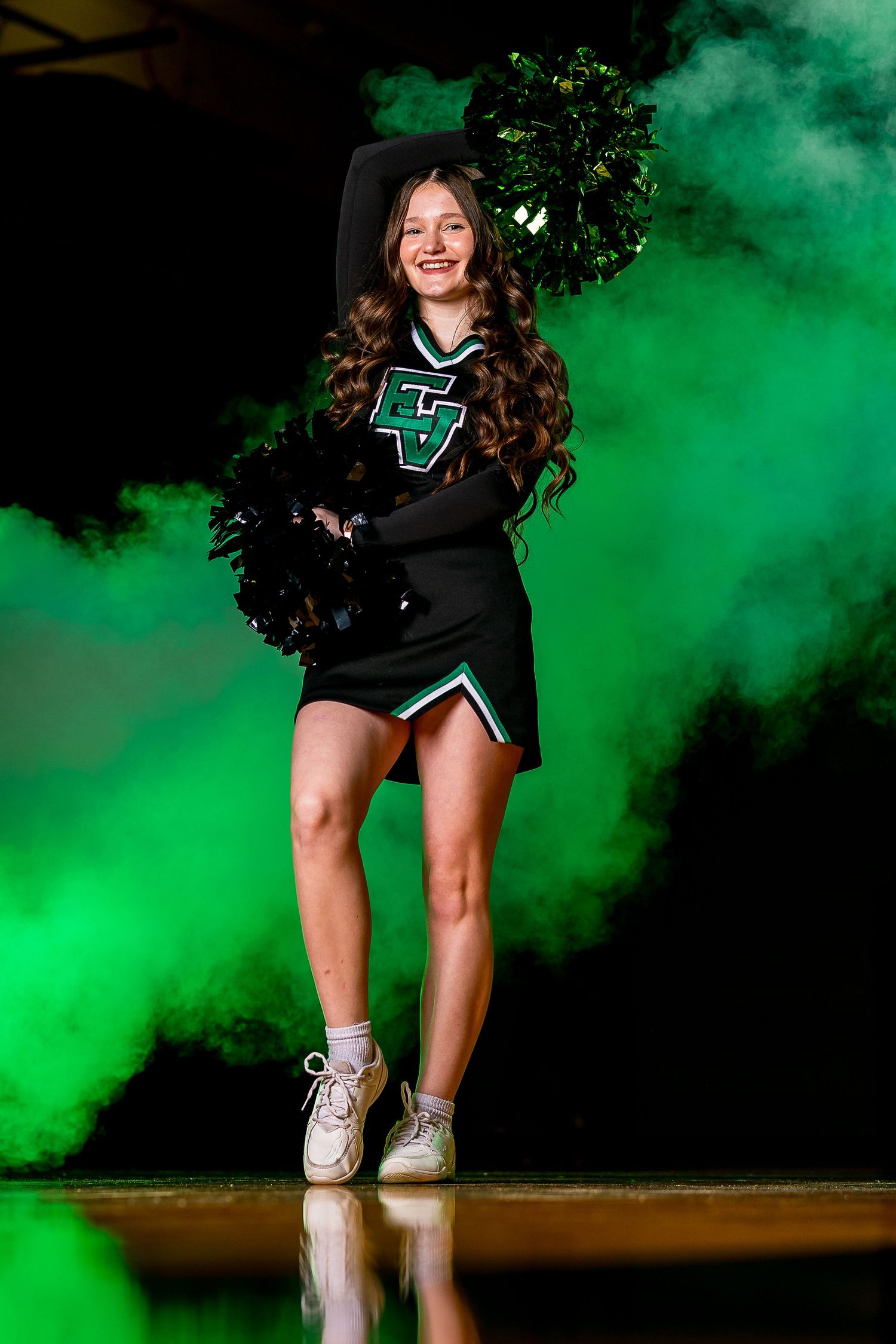 East Valley High School cheerleading portrait by Chris Elam Photography in Spokane, WA featuring a cheerleader with green smoke and pom-pom