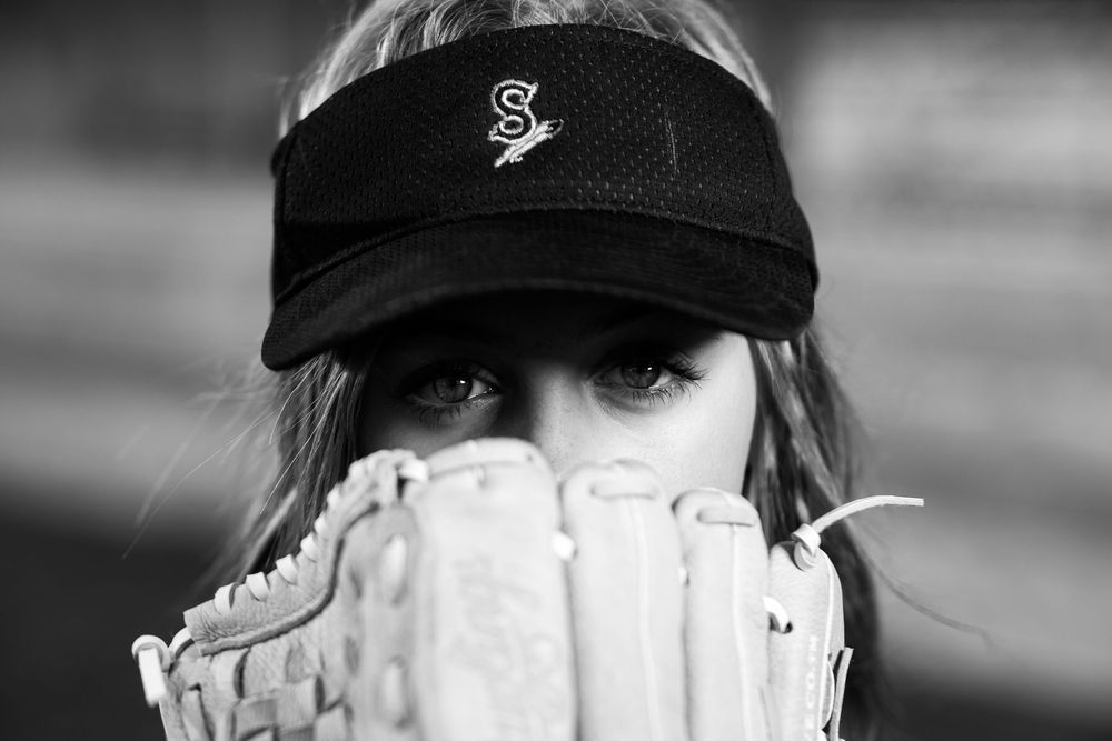 Dramatic B&W softball portrait of a player in a visor holding a glove, captured by Chris Elam Photography in the Spokane, WA area.