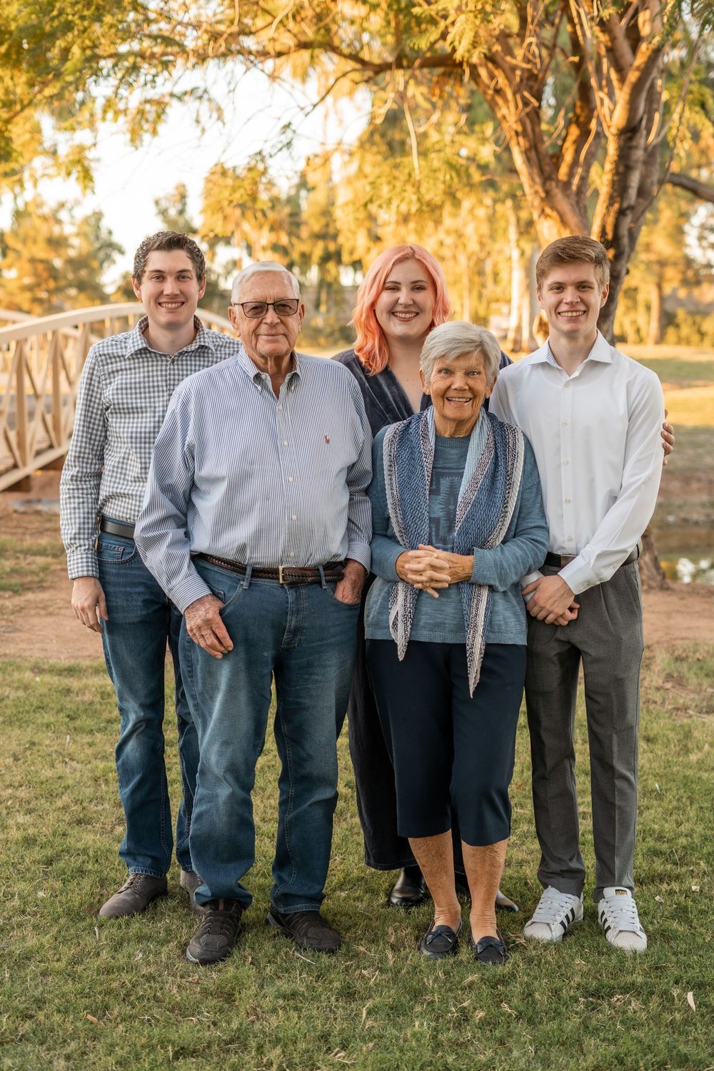 A family portrait in a park during golden hour with elderly members and younger relatives.