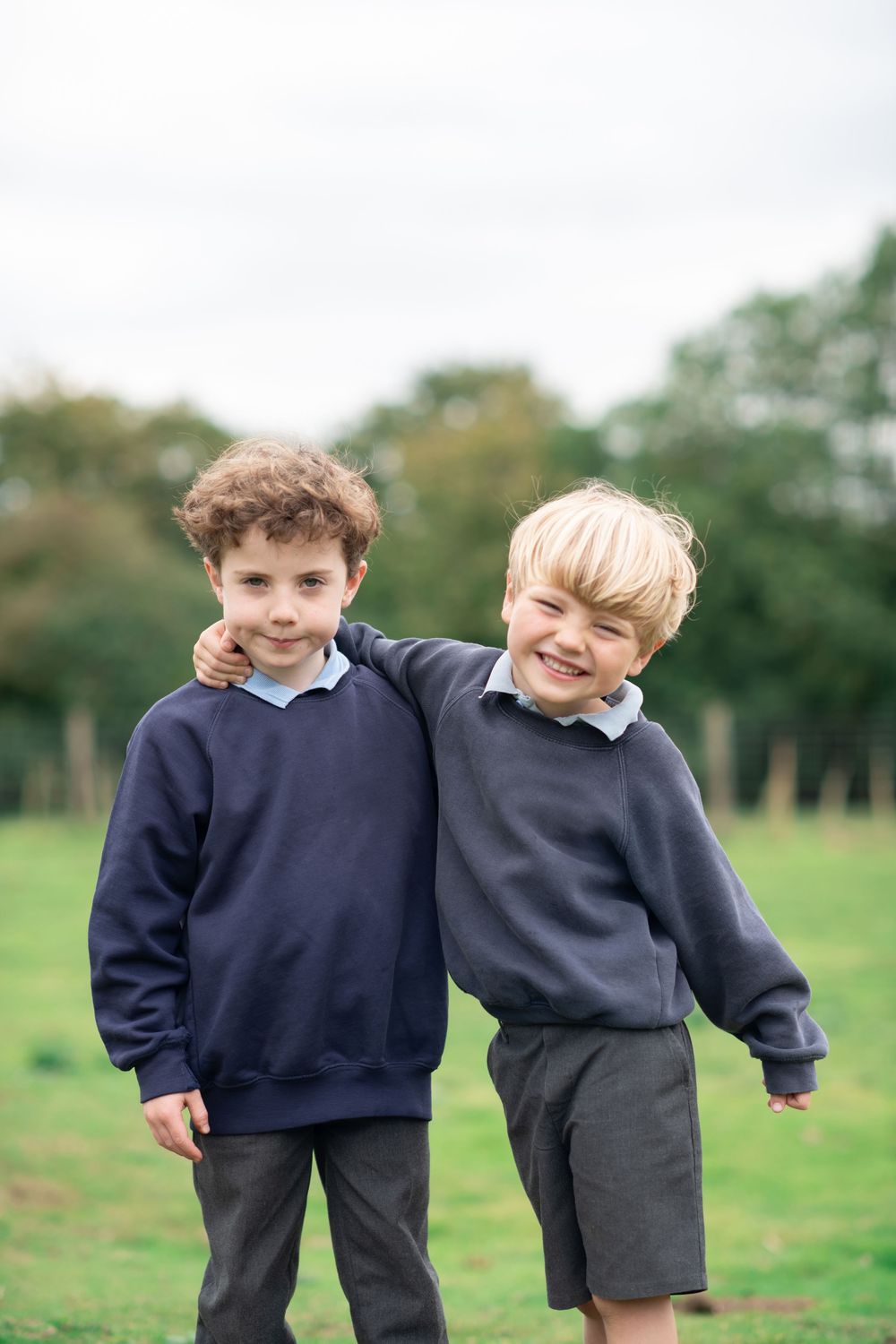 Two children in school uniforms laugh and play together on school photo day.