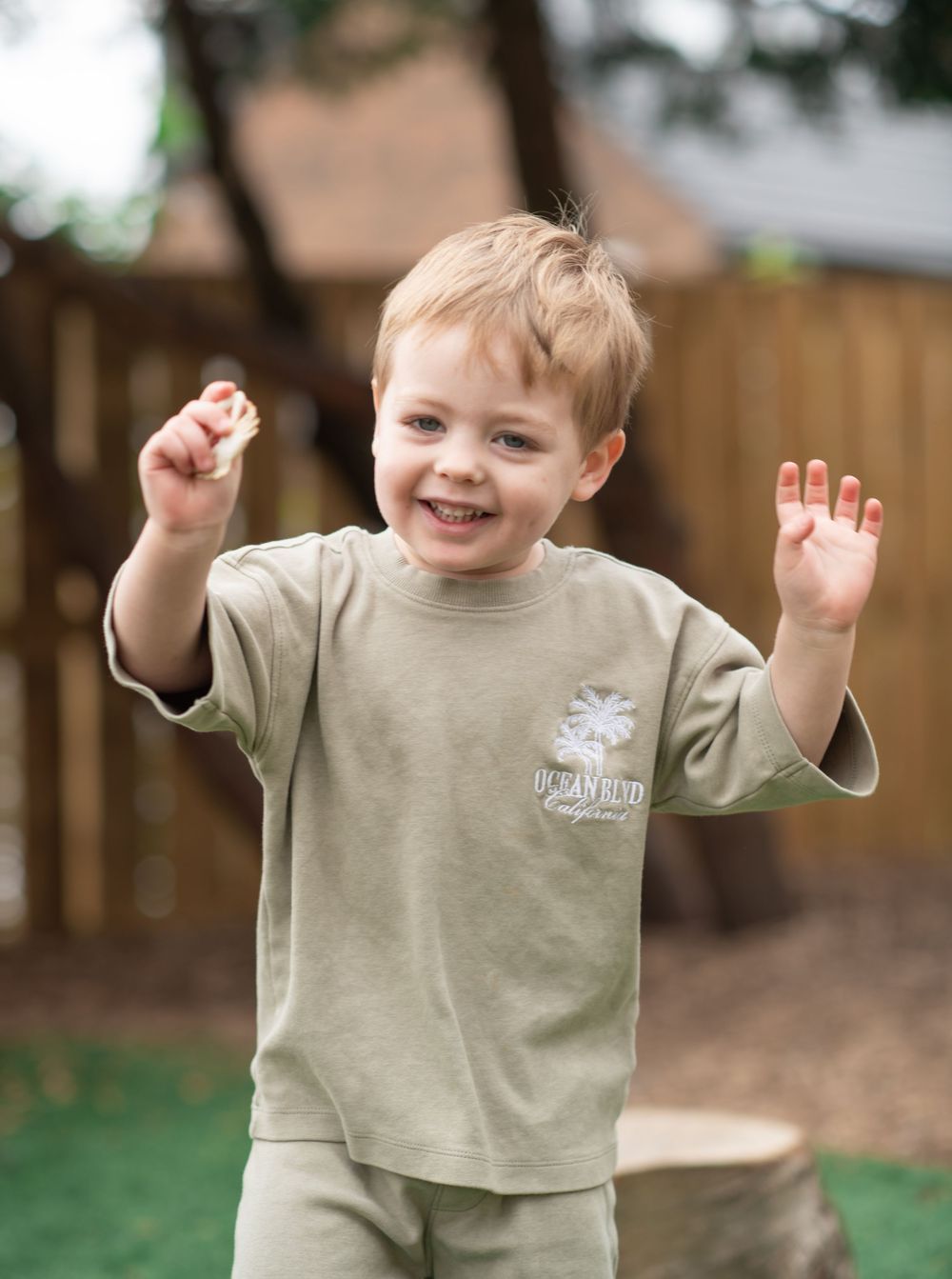 A boy dancing in a excited way with a big smile on his face at his nursery photo day in Leeds West Yorkshire.
