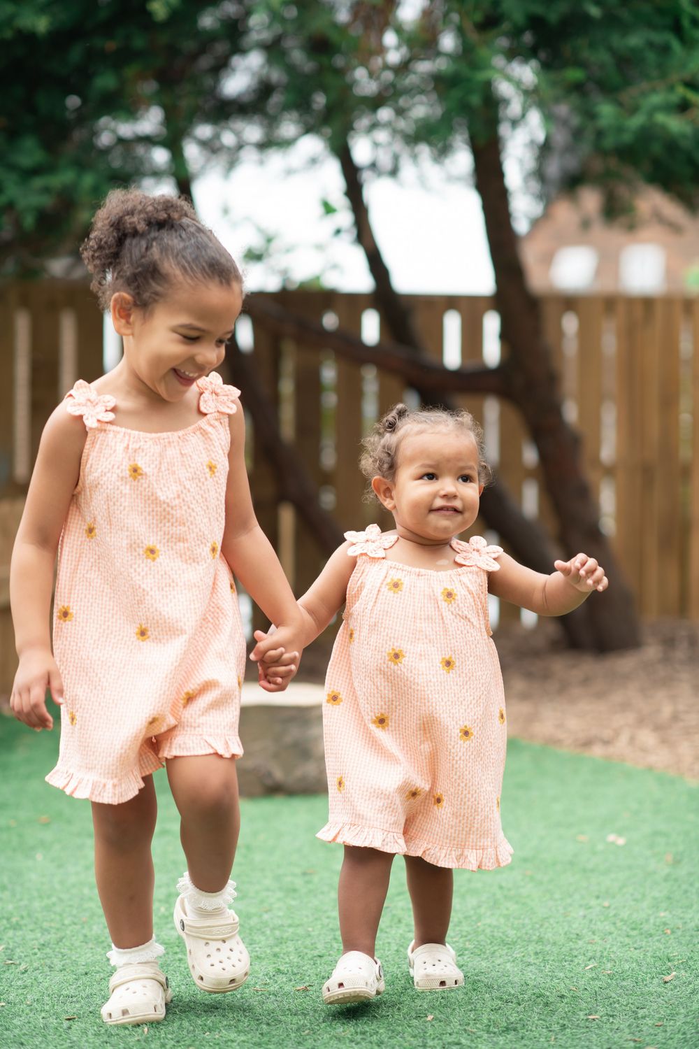 Two sisters run whilst holding hands in a natural nursery photograph in Horsforth Leeds.