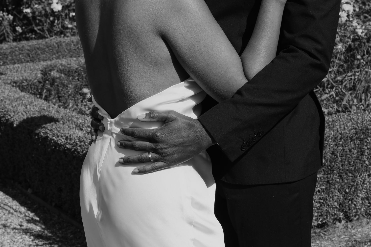 Black and white artistic photo of embracing couple in wedding attire.