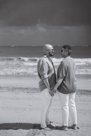 A black and white beach portrait of a couple sharing an intimate moment by the ocean.