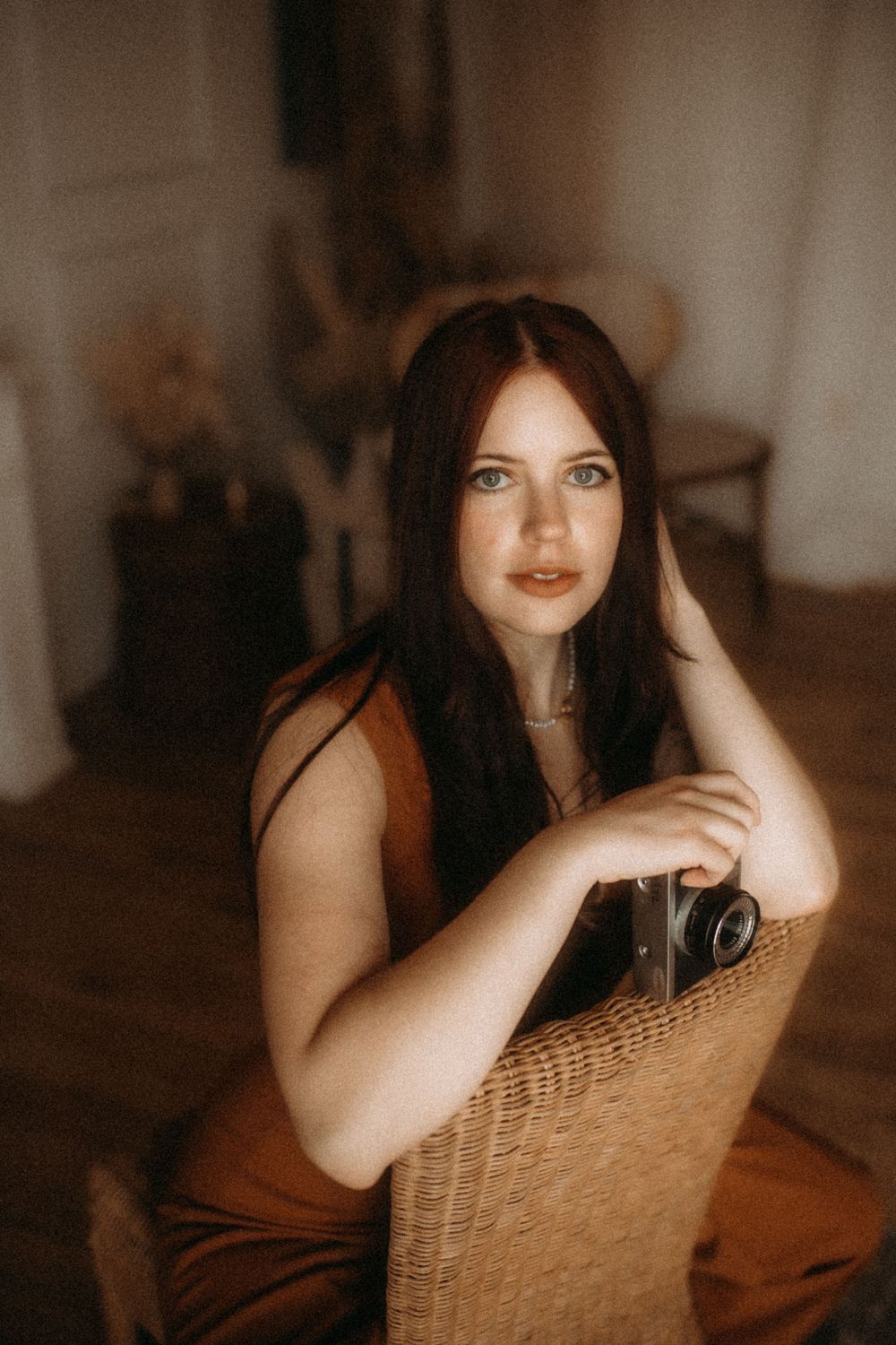A series of artistic portraits showing someone seated in a wicker chair in warm moody lighting.